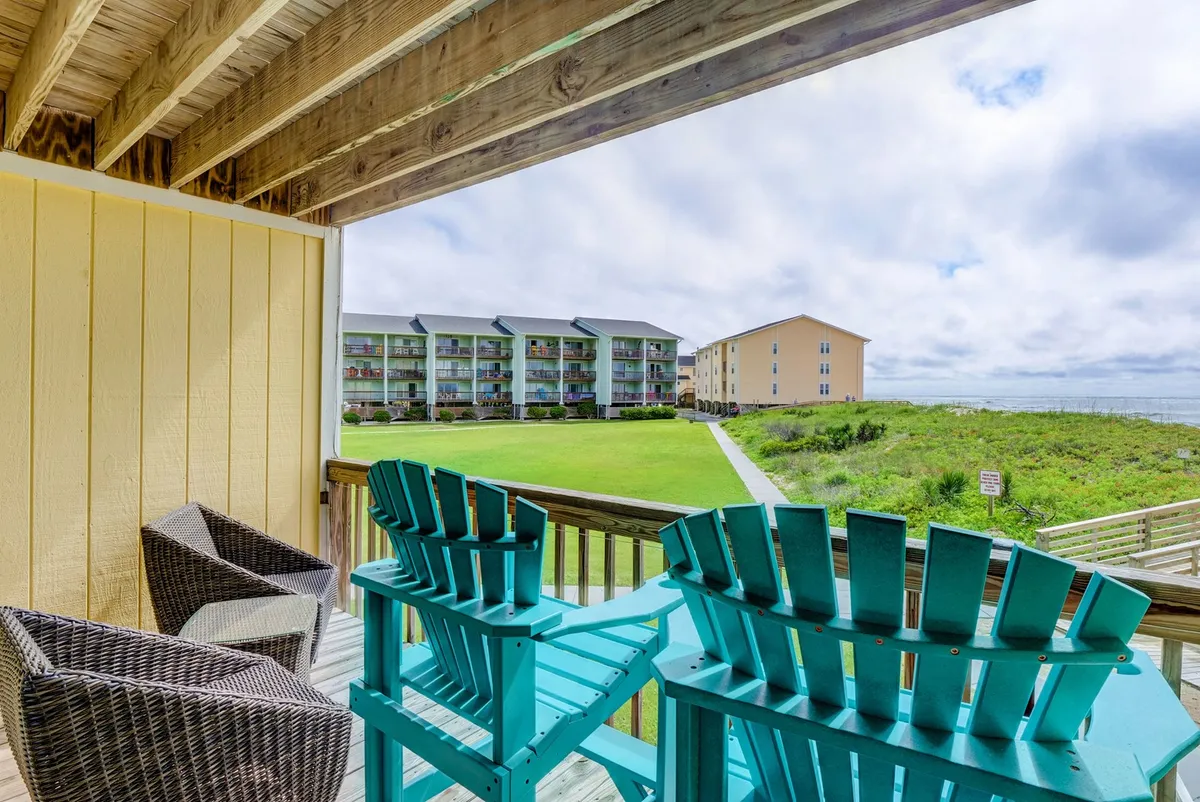 This exterior shot showcases a cozy setup with turquoise and wicker chairs arranged on a green lawn, all facing a sweeping ocean view. The inviting seating area is ideal for couples to relax, enjoy morning coffee, or share evening drinks while taking in the tranquil coastal scenery.
