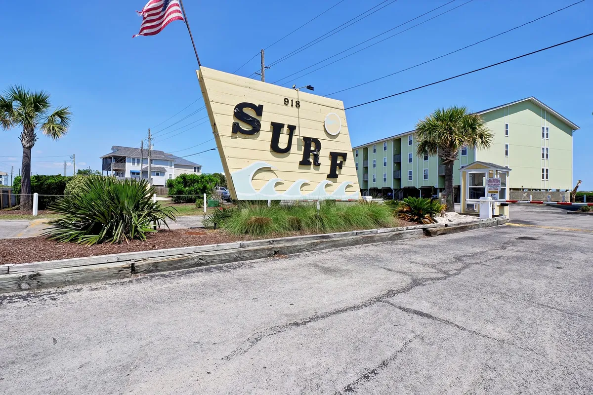 An exterior scene showcases a lively community area with a large 'SURF' sign, palm trees, and hints of gathering places—ideal for outdoor grilling and social activities under the sky.