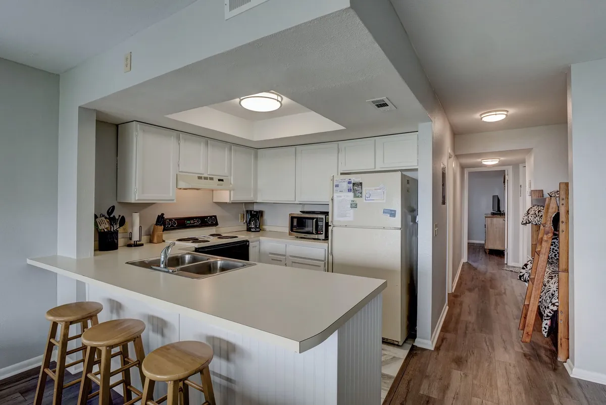 A kitchen island with stools and modern appliances is the focal point, surrounded by a welcoming, cozy atmosphere. The space is ideal for socializing, group cooking, or prepping for a night out. The layout encourages group gatherings and interactive moments.