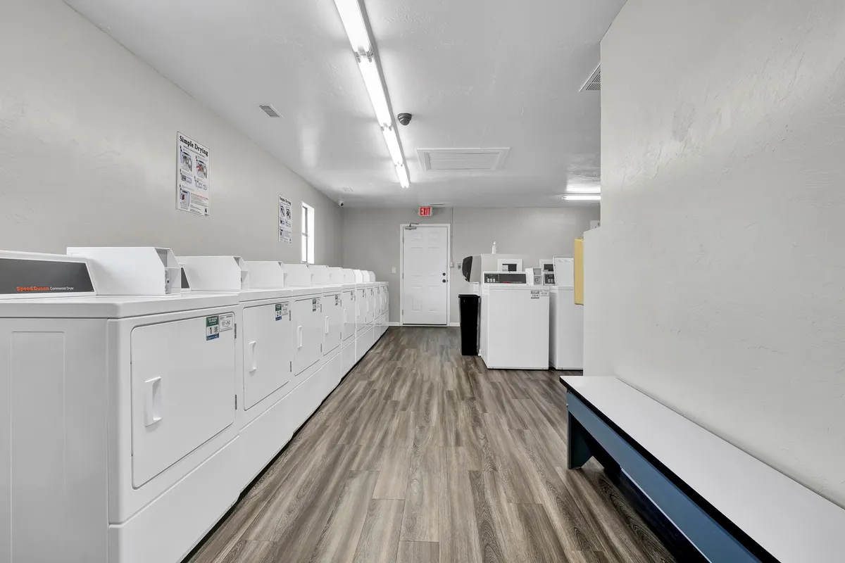 A practical laundry area with modern laundry machines and benches, set in a bright and functional space. The setup suggests convenience and ease for guests needing to recharge and refresh during their stay.