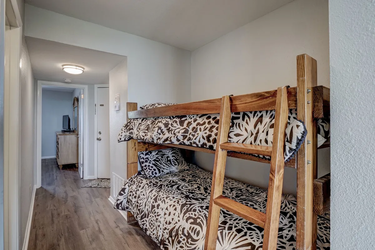 A playful and relaxed sleeping alcove with twin bunk beds dressed in decorative bedding and accessed by a sturdy wooden ladder. The space is designed for children or extra guests, providing a cozy nook for family bonding or quiet reading.